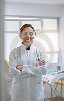 We fix your teeth with no stress. Portrait of a cheerful young female dentist standing with her arms folded while