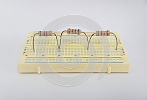 Fixed resistors connected in series electrical circuit on a protoboard, on white background.