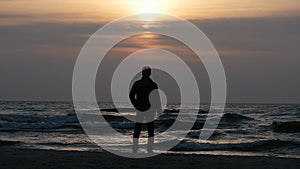 Fixed static silhouette of man at evening sea shore before sunset