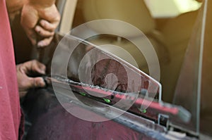 Fixing door`s car engine in automobile repair garage. Mechanics in uniform are repairing car