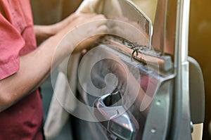 Fixing door`s car engine in automobile repair garage. Mechanics in uniform are repairing car