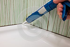 Fixing old mold destroy join lines in bathroom with caulking gun.