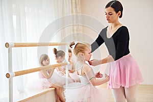 Fixing posture. Little ballerinas preparing for performance by practicing dance moves