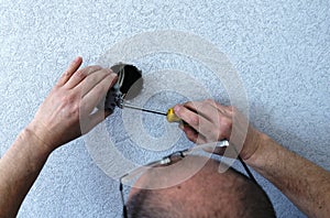 Fixing a room outlet by a man with glasses