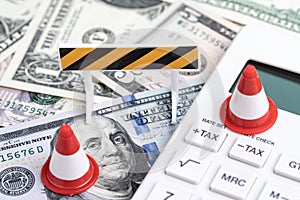 Fixing or under construction financial crisis, loan or budget concept, miniature traffic cones on white calculator with tax