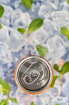 Fizzy drink in a aluminium tin can on the background of ice cubes and fresh mint leaves. Top view.