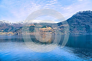 Fjord with snow covered mountains on the horizon. The water glistens in Norway