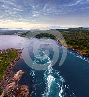 Fjord summer dusk landscape with flowing tidal current water. View from bridge (Norway