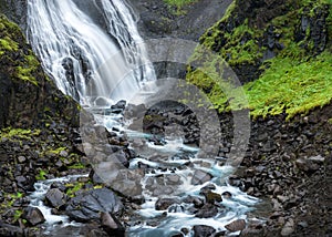 Fjordland, West Iceland - Waterfall tumbles into lush green valley