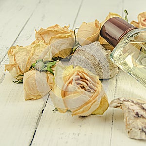 Flacon of perfume surrounded by dry buds of white roses. Presentation of cosmetic product