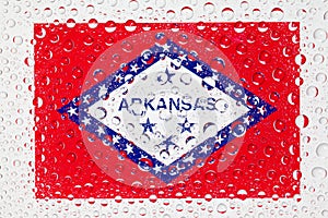 Flag of American State Arkansas behind a glass covered with rain