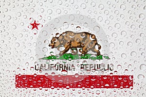 Flag of American State California behind a glass covered with ra