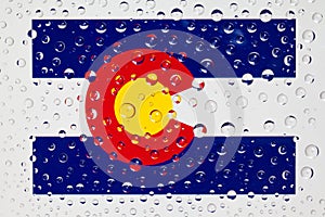 Flag of American State Colorado behind a glass covered with rain