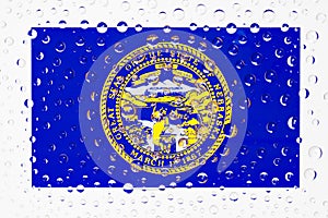 Flag of American State Nebraska behind a glass covered with rain