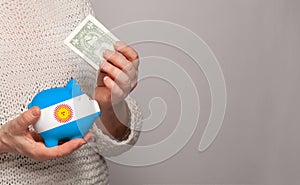 Flag of Argentina on money bank in Argentine woman hands. Dotations, pension fund, poverty, wealth, retirement concept