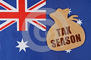 On the flag of Australia lies a cardboard figure of a money bag with the inscription - TAX SEASON