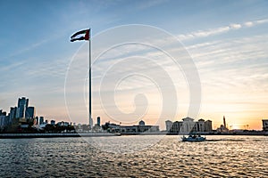 A flag on the background of beautiful tall skyscrapers at sunset. Cityscape of Flag Island, Sharjah.