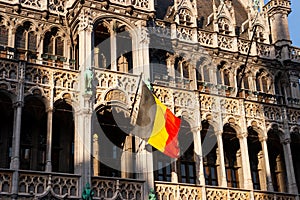 a flag of Belgium against the background of the Grand-Place Square in Brussels, Belgium.