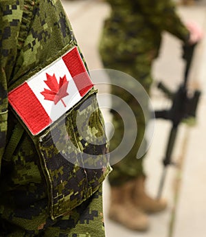 Flag of Canada on the military uniform and soldier with weapon on the background. Canadian soldiers. Canadian Army. Remembrance