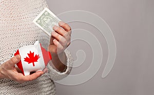 Flag of Canada on money bank in Canadian woman hands. Dotations, pension fund, poverty, wealth, retirement concept