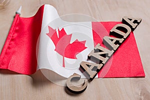 Flag of Canada, the word Canada in wooden abstract letters, wooden background