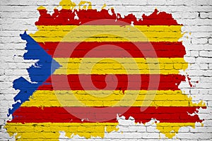 Flag of catalonia yellow, red stripe and star with watercolor splash effect on white brick wall background, national catalan symbo