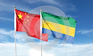 Flag of China and Republic of Gabon on cloudy sky.