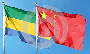 Flag of China and Republic of Gabon on cloudy sky.