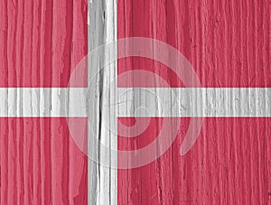 The flag of Denmark on a dry wooden surface, cracked with age. Light pale faded paint. Background, wallpaper or backdrop with