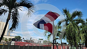 Flag of Dominican Republic waving in the wind against blue sky. Dominican flag.