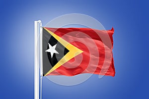 Flag of East Timor flying against a blue sky