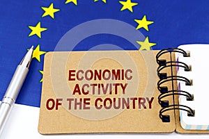On the flag of the European Union lies a pen and a notepad with the inscription - economic activity of the country