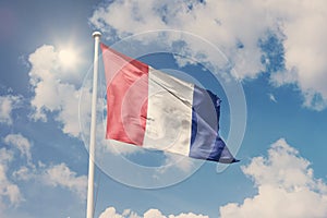 Flag of France, National symbol waving against cloudy, blue sky, sunny day