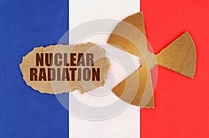 On the flag of France, the symbol of radioactivity and torn cardboard with the inscription - Nuclear Radiation
