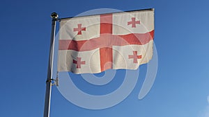 Flag of Georgia against the blue sky with sun rays and lens flare. Diplomacy concept. International relations.