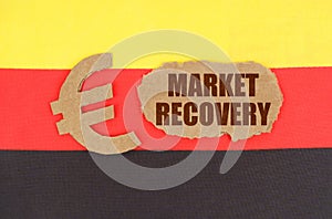 On the flag of Germany, the euro symbol and a cardboard plate with the inscription - market recovery