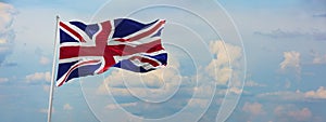 flag of Great Britain at cloudy sky background on sunset, panoramic view. Patriotic concept about Great Britan and copy space for photo