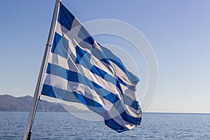 Flag of Greece on a cruise ship against greek coastline