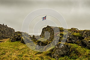 Flag of Iceland developing in the wind among the stony wild landscape.