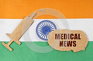 On the flag of India, a cardboard figure of a syringe and a torn cardboard with the inscription - MEDICAL NEWS