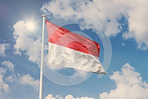 Flag of Indonesia, National symbol waving against cloudy, blue sky, sunny day