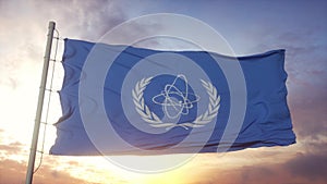 Flag of International Atomic Energy Agency IAEA waving in the wind, sky and sun background. 3d rendering