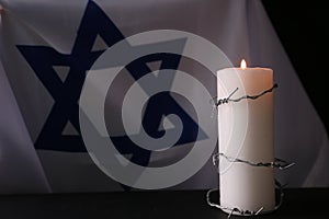 Flag of Israel, Barbed wire and burning candle on black background. Holocaust memory day