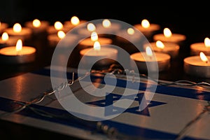 Flag of Israel, barbed wire and burning candles on black background. Holocaust memory day