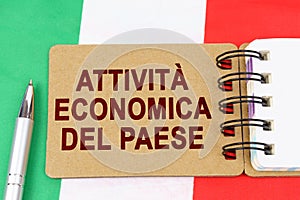 On the flag of Italy lies a pen and a notebook with the inscription - economic activity of the country