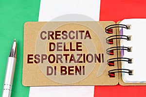 On the flag of Italy lies a pen and a notebook with the inscription - growth in exports of goods