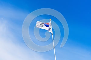 The flag of Korea on the flagpole flutters in the wind against the blue sky