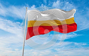 flag of Lesser Poland Voivodeship, wojewodztwo malopolskie , Poland at cloudy sky background on sunset, panoramic view. Polish