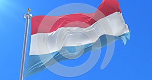 Flag of Luxembourg waving at wind with blue sky in slow, loop