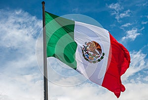 Flag of Mexico over blue cloudy sky photo